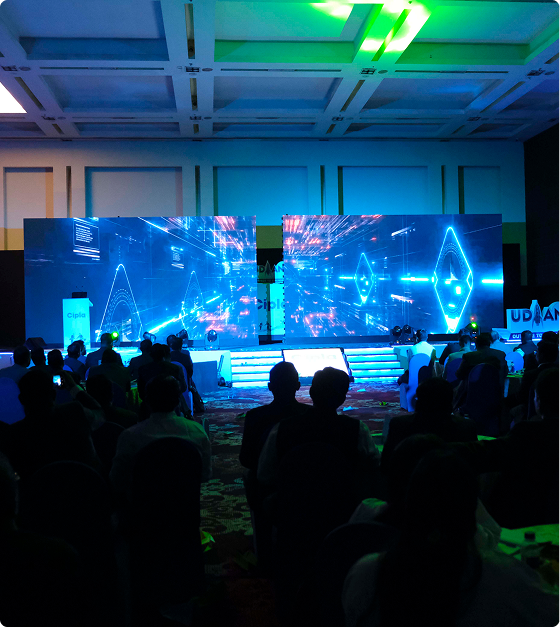 Audience watching a large LED screen presentation at the UDAAN conference