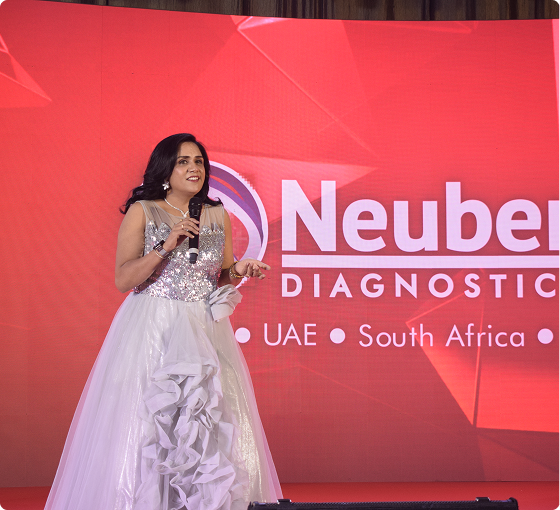 Host on stage at the Neuberg Diagnostics launch event in a white gown